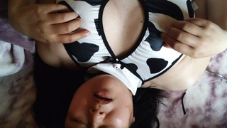 A Asian woman cosplaying as a cow has an climax while masturbating her nipples.